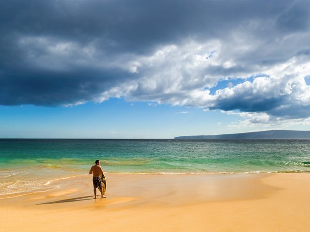 A surfer heading out into the Pacific